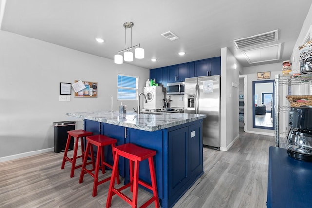 kitchen featuring light stone counters, visible vents, blue cabinetry, and appliances with stainless steel finishes