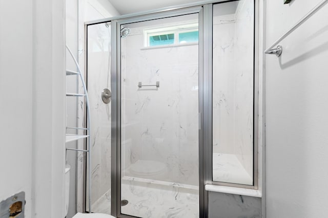 bathroom with a marble finish shower and toilet