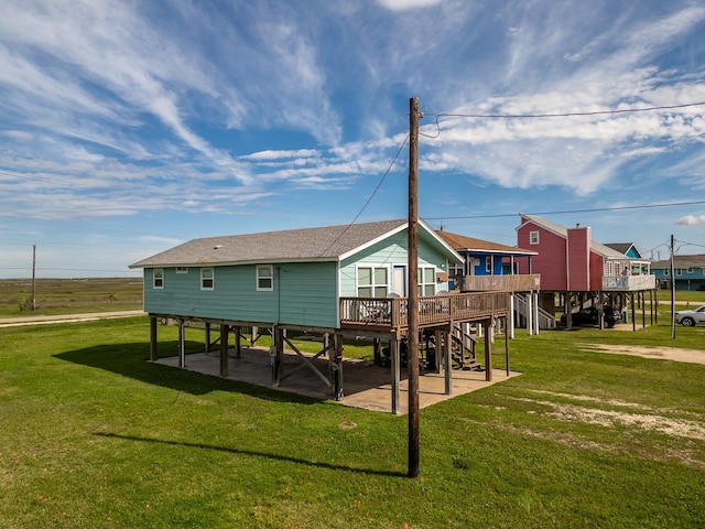 back of house featuring a lawn, a patio, roof with shingles, a wooden deck, and stairs