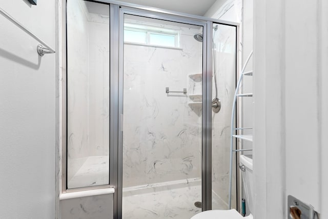 bathroom with a marble finish shower and toilet