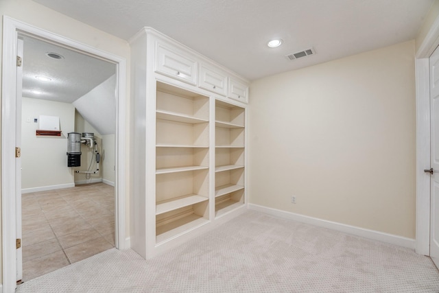 interior space with light carpet, built in features, a textured ceiling, baseboards, and vaulted ceiling