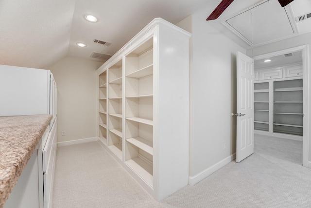 spacious closet featuring attic access, light colored carpet, visible vents, and vaulted ceiling