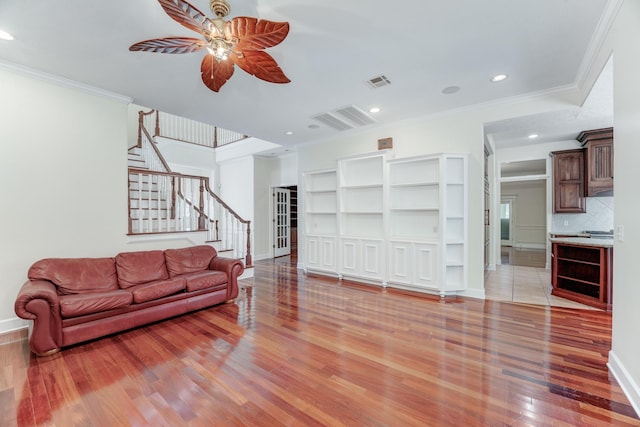 living room featuring visible vents, stairway, ornamental molding, light wood-style floors, and a ceiling fan