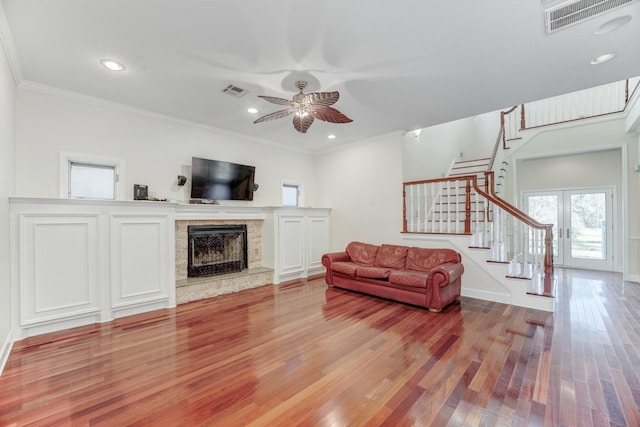 living room with visible vents, wood finished floors, stairway, a fireplace, and ceiling fan