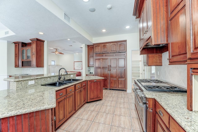 kitchen with high end appliances, light stone countertops, ceiling fan, a sink, and backsplash