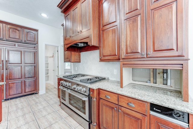 kitchen featuring double oven range, light stone countertops, backsplash, and light tile patterned flooring