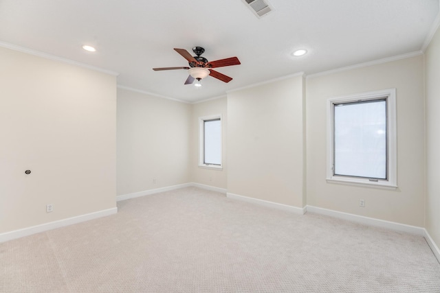 empty room with a ceiling fan, visible vents, baseboards, crown molding, and light colored carpet