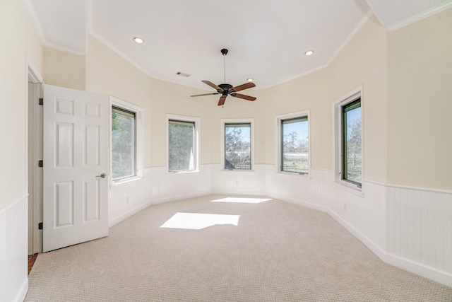 carpeted empty room featuring visible vents, ornamental molding, a ceiling fan, recessed lighting, and wainscoting