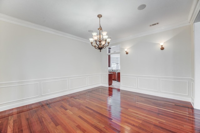 unfurnished room with ornamental molding, wood finished floors, visible vents, and a chandelier