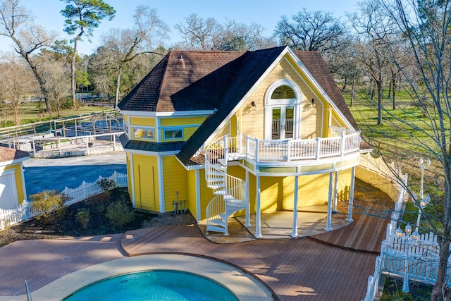 exterior space featuring fence, a wooden deck, a hot tub, stairs, and french doors