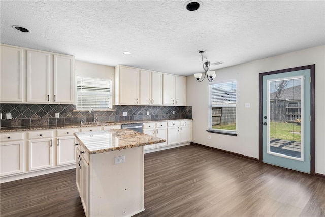 kitchen with dark wood-style floors, a notable chandelier, dishwasher, and a sink