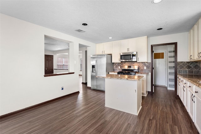 kitchen with visible vents, a kitchen island, dark wood-style floors, white cabinetry, and stainless steel appliances