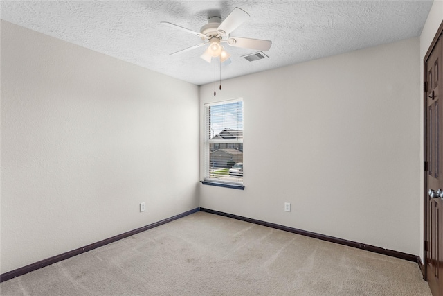 spare room featuring baseboards, a ceiling fan, visible vents, and light carpet