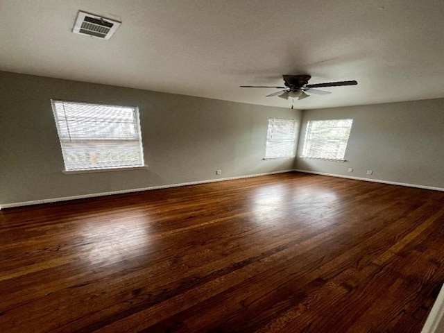 spare room with visible vents, baseboards, a ceiling fan, and dark wood-style flooring