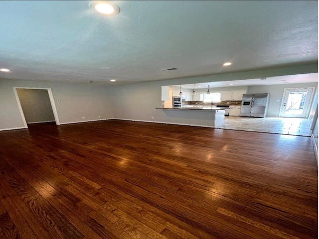 unfurnished living room with recessed lighting and dark wood-type flooring