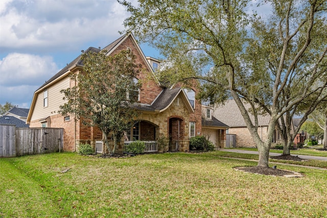 view of front of home featuring stone siding, an attached garage, a front yard, and fence