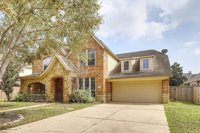 view of front of house featuring a front yard, fence, driveway, a garage, and brick siding