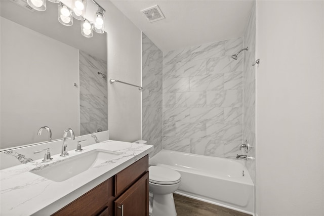 bathroom with visible vents, toilet, wood finished floors,  shower combination, and vanity