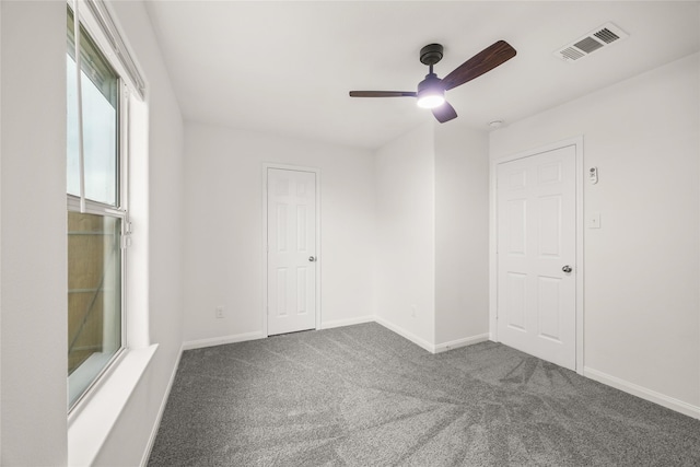 carpeted spare room with a ceiling fan, visible vents, and baseboards