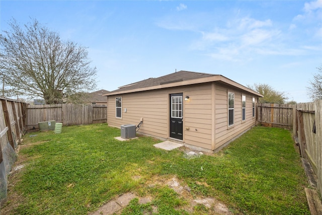 rear view of house featuring a yard, central air condition unit, and a fenced backyard