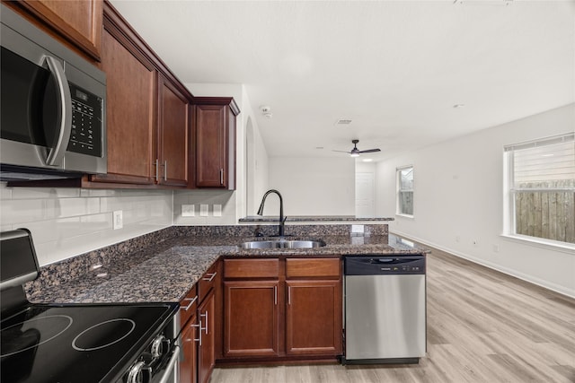 kitchen featuring a ceiling fan, a sink, light wood-style floors, appliances with stainless steel finishes, and a peninsula