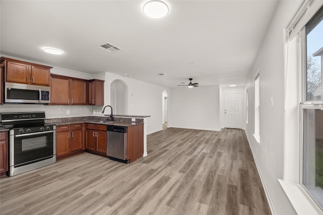 kitchen with visible vents, a sink, arched walkways, appliances with stainless steel finishes, and a peninsula