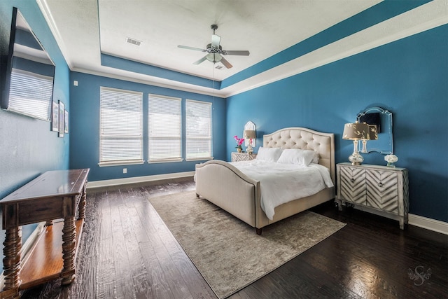 bedroom with visible vents, ceiling fan, baseboards, hardwood / wood-style flooring, and a raised ceiling