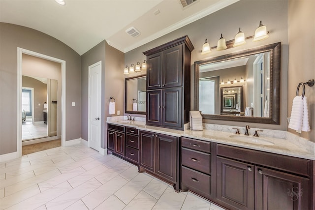 full bathroom with double vanity, vaulted ceiling, baseboards, and a sink