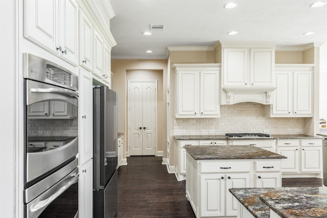 kitchen featuring dark stone countertops, visible vents, appliances with stainless steel finishes, and crown molding