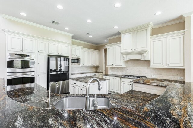 kitchen featuring visible vents, custom range hood, a sink, appliances with stainless steel finishes, and crown molding