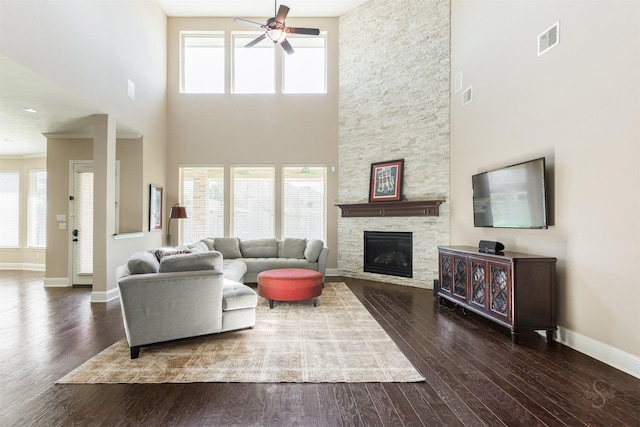 living room with a fireplace, wood finished floors, a ceiling fan, and visible vents