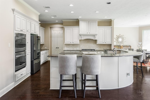 kitchen with backsplash, crown molding, a kitchen bar, dark wood-style floors, and stainless steel appliances