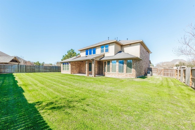 back of house with a yard, brick siding, a fenced backyard, and a patio area