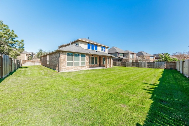 back of property with a yard, a fenced backyard, brick siding, and roof with shingles