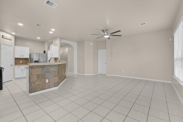 kitchen with arched walkways, visible vents, stainless steel fridge, and ceiling fan