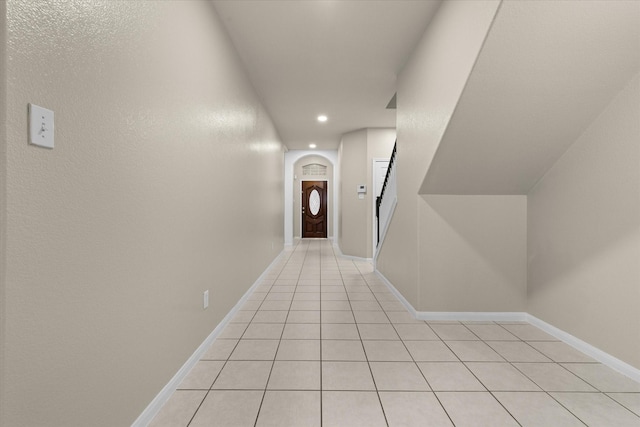 hall featuring light tile patterned floors, baseboards, arched walkways, and recessed lighting