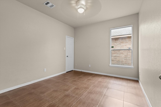 unfurnished room featuring plenty of natural light, a ceiling fan, visible vents, and baseboards