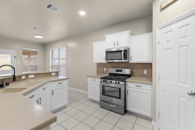 kitchen featuring visible vents, appliances with stainless steel finishes, decorative backsplash, and a sink