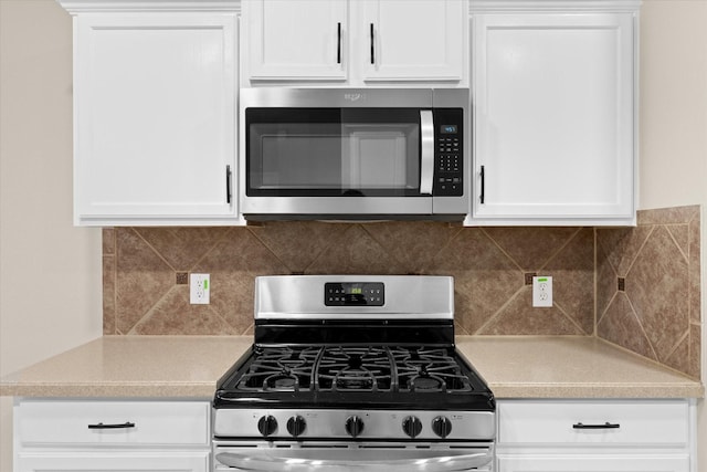 kitchen featuring stainless steel appliances, white cabinets, and light countertops