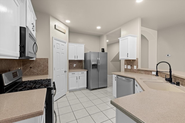 kitchen with light countertops, light tile patterned floors, appliances with stainless steel finishes, white cabinets, and a sink