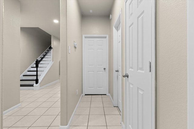 hall with stairway, light tile patterned floors, and baseboards