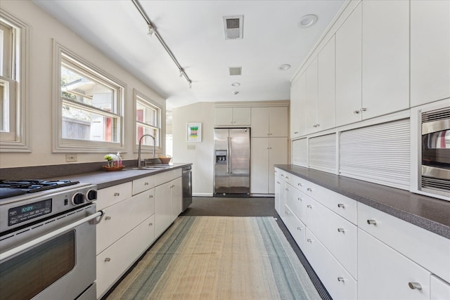 kitchen with dark countertops, visible vents, stainless steel appliances, and a sink