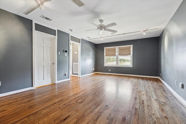 empty room featuring visible vents, baseboards, ceiling fan, and wood finished floors