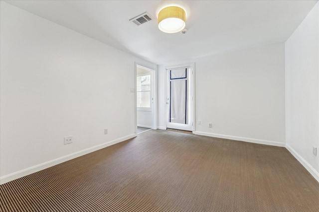 unfurnished room with baseboards, visible vents, and dark colored carpet