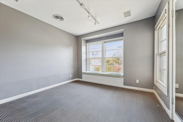 unfurnished room featuring dark colored carpet, visible vents, and baseboards