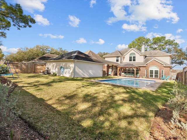 rear view of house featuring a fenced backyard, a gazebo, a yard, a fenced in pool, and a chimney