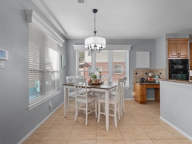 dining space featuring light tile patterned floors, baseboards, and a chandelier