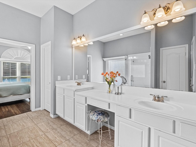 bathroom with double vanity, a shower with shower door, tile patterned floors, and a sink