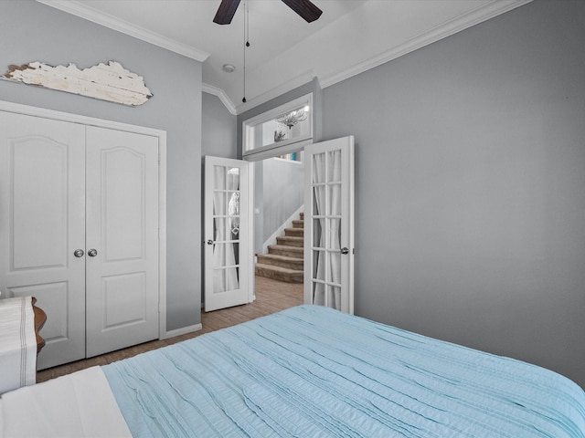 bedroom with a ceiling fan, wood finished floors, french doors, a closet, and crown molding