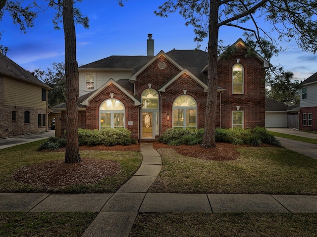 traditional-style home with a garage, brick siding, roof with shingles, and a chimney